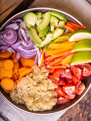 Salad bowl with quinoa, carrots, avocado, onion, pepper, tomato with slices of lime close-up - vegetarian dish, buddha bowl