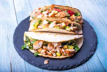 Tacos with vegetables, avocado and chicken breast on a slate dish - traditional mexican appetizer