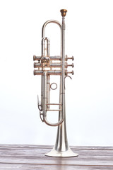 Trumpet instrument over white background. Trumpet on wooden table, vertical image. Vintage instrument of classical music.