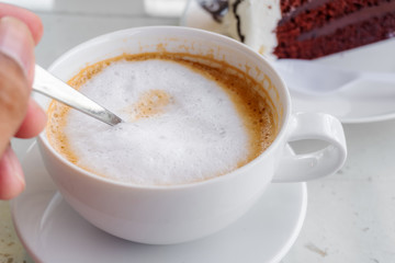 Latte coffee in a white cup on white table