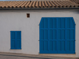 Fronansicht eines Hauses mit blauem Garagentor und blauen Fensterläden
