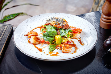 salad with avocado, shrimp, spinach and chicken fillet in a sweet and sour sauce. Warm grilled salad on white plate. Restaurant food background. clean eating, dieting food concept. Seafood