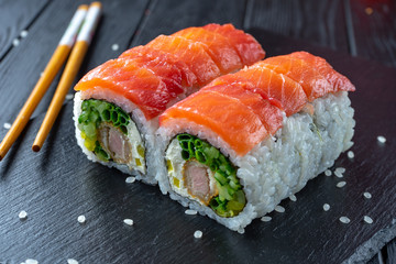 Close up sushi roll with tuna, cream cheese and salmon. Sushi on stone dark plate on black wooden...