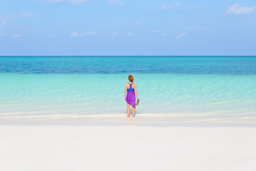 Fototapeta na wymiar Woman walking on tropical beach. Rear view white sand beach turquoise trasparent water caribbean sea real people. Indonesia Kei Islands Moluccas travel destination.