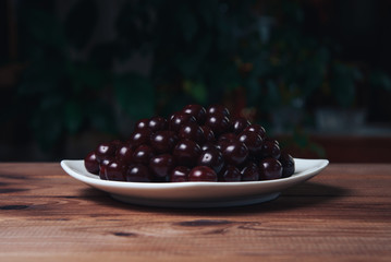 Cherry on a white plate on a wooden table.