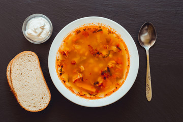 Bean soup with smoked bone served with bread slices and seasoning – Food background of a dark ardesia stone board with meal
