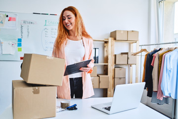 Cheerful young businesswoman checking deliveries in modern office and storage space