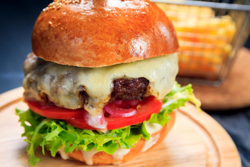 American fast food. Juicy American cheeseburger with beef cutlets, sauce and tomato on a black background.