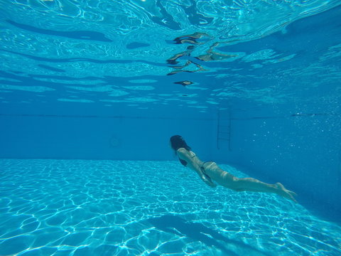 underwater shooting woman in a black swimsuit swimming in the pool