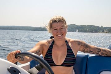 Blond caucasian woman driving a sport boat