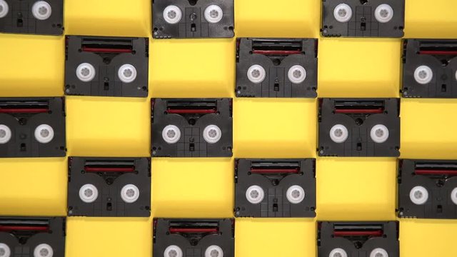 Vintage mini DV cassette tapes used for filming back in a day. Pattern made of plastic video tapes on yellow background