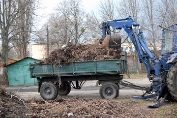 Cleaning dry branches and grass on city streets loading into truck trailer.