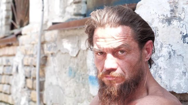 Homeless man looks at the camera and talks. Real person with no fixed abode. Down-and-out person on the street