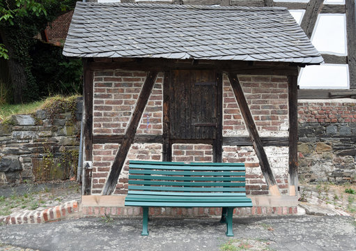 Empty green bench in front of very small half-timbered structure in Germany