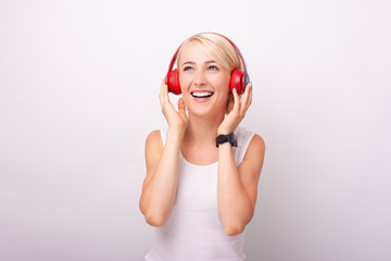 Photo aof cheerful blonde woman listening music at wireless headphones and having fun