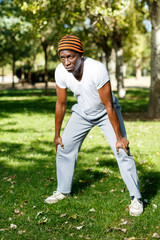 Active african  american man doing exercises for legs, workout in park