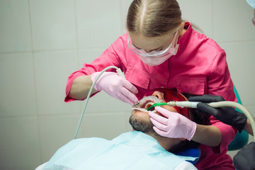 Professional teeth cleaning. Dentist cleans the teeth of a male patient.