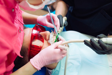 Professional teeth cleaning. Dentist cleans the teeth of a male patient.