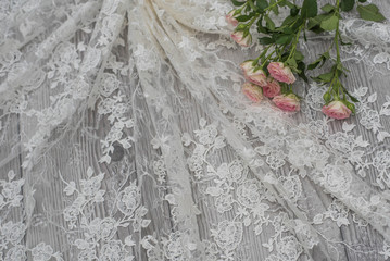 White wooden background with white spring flowers roses and lace ribbon. Happy womans day. The...