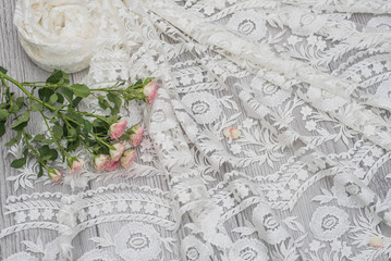 White wooden background with white spring flowers roses and lace ribbon. Happy womans day. The texture of lace on wooden background.