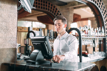 small business, people and service concept - happy man or waiter in apron at counter with cashbox...