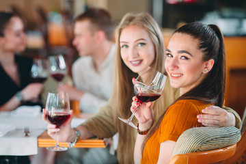 Friends have fun drinking wine, talking and smiling in the restaurant.