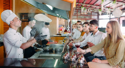 The chef prepares food in front of the visitors in the restaurant