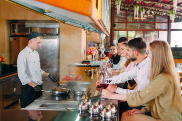 The chef prepares food in front of the visitors in the restaurant