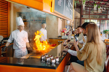 The chef prepares food in front of the visitors in the restaurant