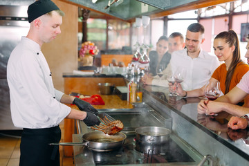 The chef prepares food in front of the visitors in the restaurant