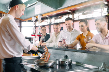 The chef prepares food in front of the visitors in the restaurant