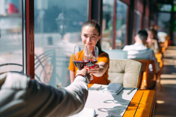 A young couple drinking wine in a restaurant near the window.