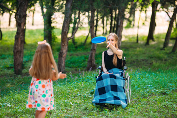 A young disabled girl plays Frisbee with her younger sister. Interaction of a healthy person with a disabled person