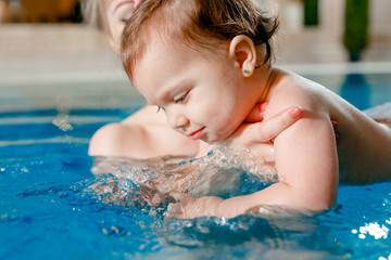 Mom and baby swim in the pool.