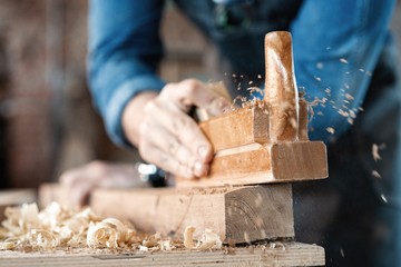 carpenter working with plane on wooden background.