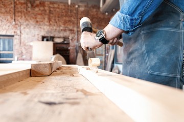 Carpenter working on woodworking machines in carpentry shop. A man works in a carpentry shop.