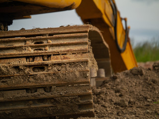 Excavator working in the field, Dirty tracks, Arm digging hole in the ground, Selective focus, Heavy machinery in action. Building industry.