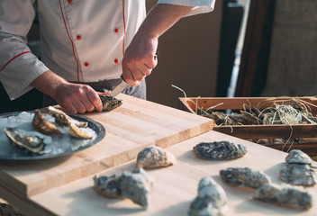Opening the hollow and flat oysters. Chef opens oysters in the restaurant.