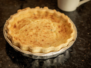 Quiche lorraine on a black reflective surface,
