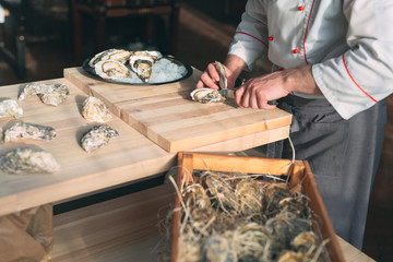Opening the hollow and flat oysters. Chef opens oysters in the restaurant.