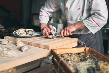 Opening the hollow and flat oysters. Chef opens oysters in the restaurant.