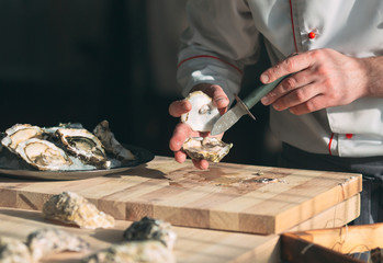 Opening the hollow and flat oysters. Chef opens oysters in the restaurant.