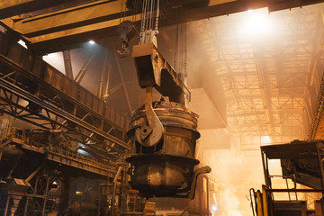 Melting of metal in a steel plant. High temperature in the melting furnace. Metallurgical industry. Factory for the manufacture of metal pipes. Bucket for feeding metal into molds.