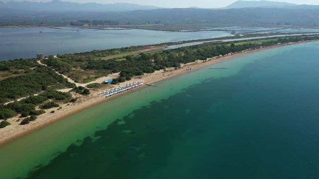 Aerial drone video of iconic secluded sandy beach with emerald sea in island of Sfaktiria next to bay and famous beach of Divari (chrysi akti), Messinia, Gialova, Peloponnese, Greece