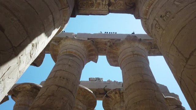 Walking through Karnak Temple Complex columns with sunlight, ancient Egypt ruins
