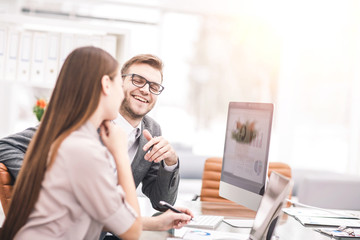 Manager and accountant are sitting and discussing financial charts with the profits of the company in the workplace