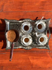 Four cups of traditional Turkish coffee, on the wooden table.