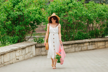 Young woman holding pink cotton grocery bag with vegetables. Reusable eco bag for shopping. Zero waste concept.