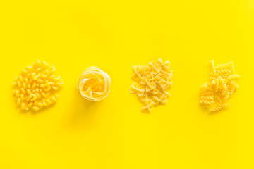 Italian pasta on yellow table background top view