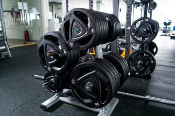Fototapeta premium Modern light gym. Sports equipment in gym. Barbells of different weight on rack.